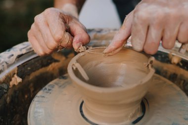 Potter tekerlek üzerinde kil kaseyi şekillendiriyor. Çamur, çömlekçi çanağı oluştururken el altında yavaşça döner. Tekerlekteki kil kalıpları çömlek sanatını ve yeteneğini ön plana çıkarıyor