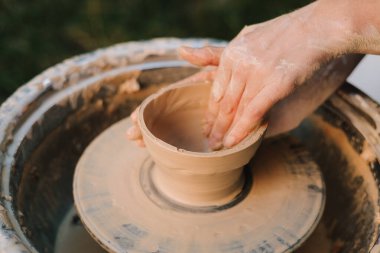 Potter tekerlek üzerinde kil kaseyi şekillendiriyor. Çamur, çömlekçi çanağı oluştururken el altında yavaşça döner. Tekerlekteki kil kalıpları çömlek sanatını ve yeteneğini ön plana çıkarıyor