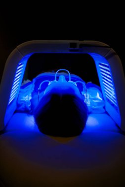 Hasta, yüz gençleştirme için LED fototerapi sırasında gözlük takıyor.