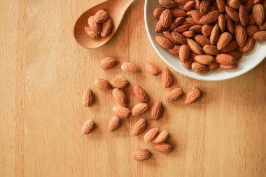 Tahta arka planda bir kasede badem.