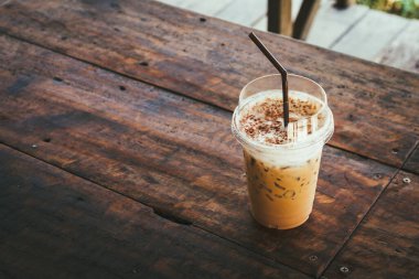 Eski ahşap bir masada öğütücüde bir fincan soğuk kahve. 