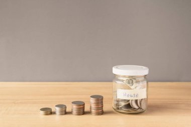 Bozuk paralar ve paralar cam kavanozda, tahta masada.