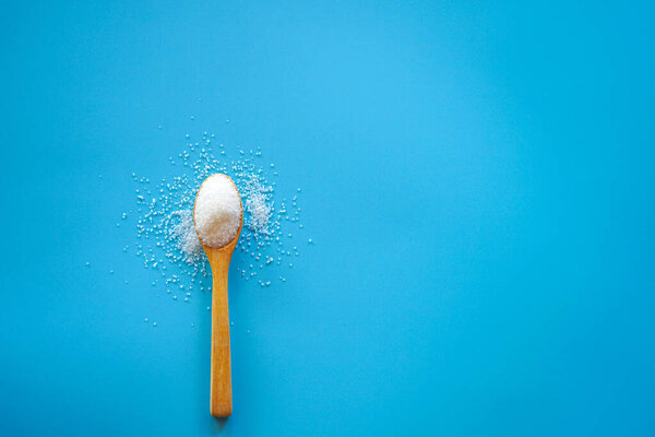 spoon with sugar on blue  background