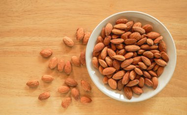 Tahta arka planda bir kasede badem.