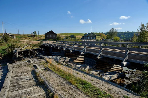 Alte zerstörte Holzbrücke über einen flachen ländlichen Fluss — Stockfoto