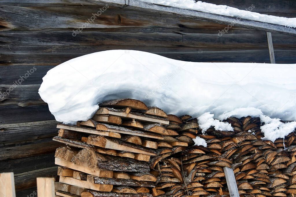 Wood piled in a woodpile under the snow in winter. High quality photo