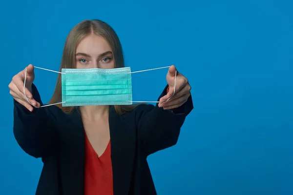 Kızın elinde kol mesafesinde tıbbi bir maske var.