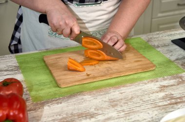 Yemek pişirmek için kesme tahtasındaki sebzeleri dilimliyorum.