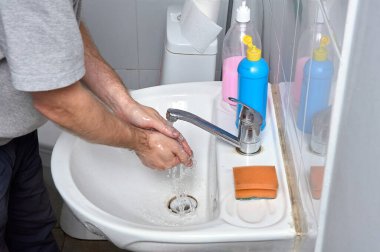 Ellerini musluğun altındaki lavaboda yıkıyorsun.