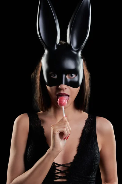 Tavşan maskeli bir kadın lolipop emer.