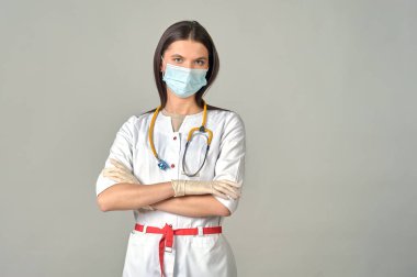 Tıbbi maskeli genç bir doktor ve boynunda sarı bir steteskop olan beyaz önlüklü.