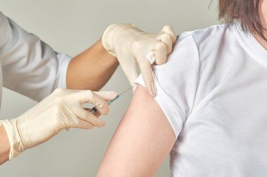 Hemşire yakın plan çekimde aşı oluyor.