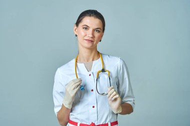 Boynunda sarı bir steteskop olan beyaz önlüklü genç bir doktor.