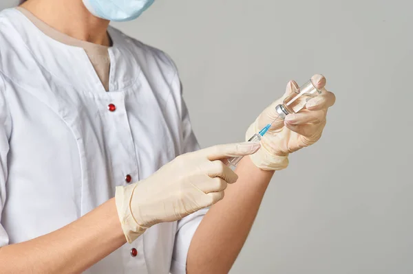 A nurse taking medicine into a syringe from a bottle close-up. Preparation of the coronavirus vaccine-Covid-19.