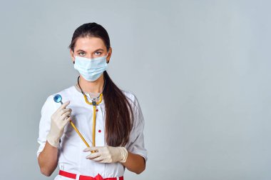 Tıbbi maskeli bir doktor ve steteskoplu beyaz önlüklü bir doktor.