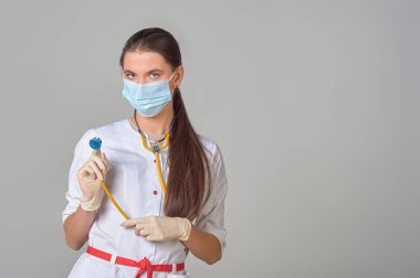 Tıbbi maskeli bir doktor ve boynunda steteskop olan beyaz önlüklü bir doktor.