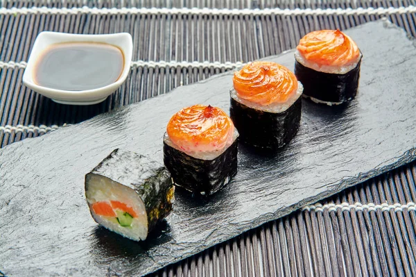 Rolos com teriyaki de salmão em um suporte de pedra, cozinha japonesa — Fotografia de Stock
