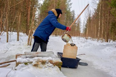 Bir adam kışın plastik fıçıdaki bir kaynaktan su çeker.