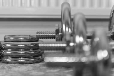 Arka plandaki en büyük ağırlığa odaklanan bir sıra halterin siyah beyaz fotoğrafı