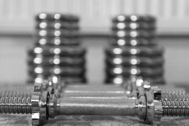 Evde yerde ağırlık kaldırma ekipmanlarının siyah beyaz fotoğrafı.