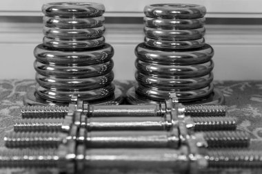 Evde yerde ağırlık kaldırma ekipmanlarının siyah beyaz fotoğrafı.