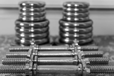 Evde yerde ağırlık kaldırma ekipmanlarının siyah beyaz fotoğrafı.