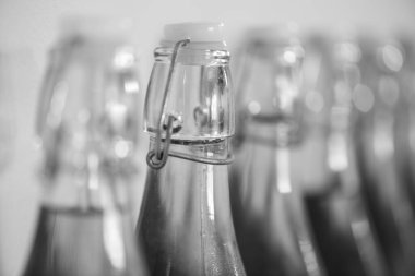 Bir sıra ev yapımı elma şarabı şişesinin yoğunlaştırılmış siyah beyaz fotoğrafı.