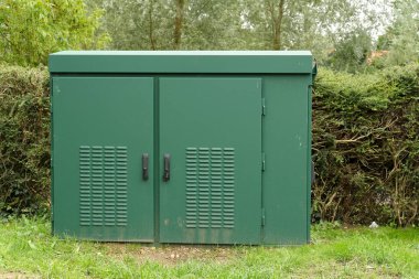 Bir çite karşı yeşil iletişim dolabı