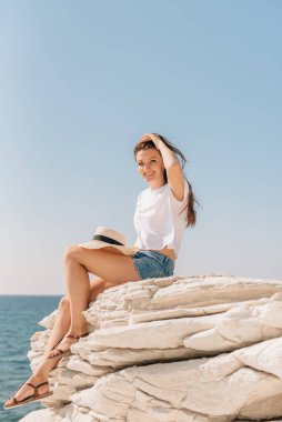 Şortlu güzel bir kız ve Kıbrıs 'ta deniz kenarında bir şapka.