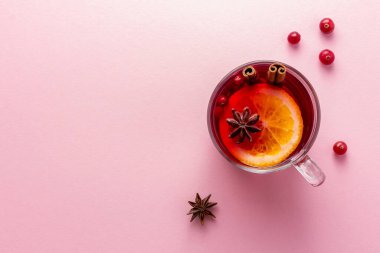 Cam bir bardak noel şarabı ya da fotokopi çekilen pembe arka planda bir eldiven.