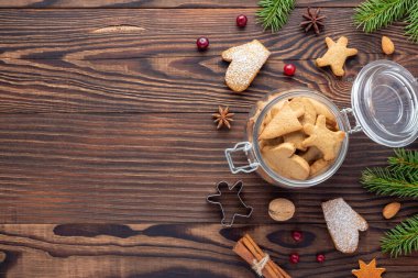 Noel tatlıları - Noel pastanesi malzemeleri arasında bisküviler ve ahşap masa üzerinde köknar dalları olan bir kavanoz..