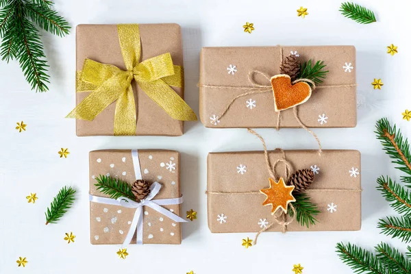 Four Christmas and New Year presents wrapped in eco paper on white wooden background