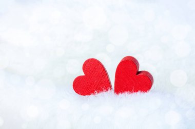 Pofuduk, parlak arka planda iki kırmızı tahta kalp. Sevgililer Günü veya Düğün için yakın plan.