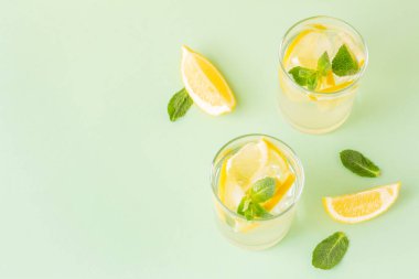 Yeşil arka planda limon ve nane yapraklı iki bardak ferahlatıcı yaz içeceği. Antioksidan narenciye suyu ya da detoks için limonata. Boşluğu kopyala