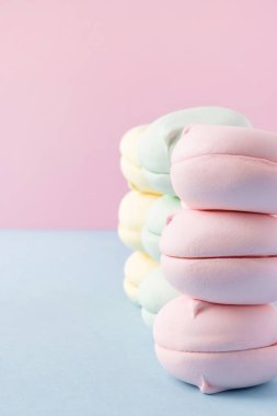 Pastel pembe ve mavi arka planda renkli şekerleme yığınları. Kopya alanı olan yuvarlak şekilli şekerleme.