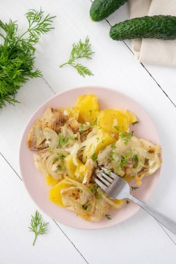 Beyaz ahşap zemin üzerinde soğanlı balık fileto ve patates. Akşam yemeği için taze salatalık ve sebze pişirdim..