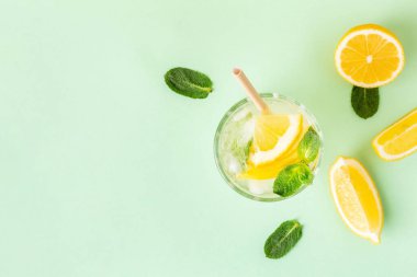 Limonlu buzlu su ya da yeşil arka planda naneli limonata. Yaz sıcağı için bir bardak taze meyve suyu..