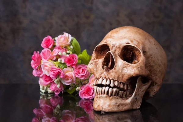 Artificial flowers with human skull — Stock Photo, Image