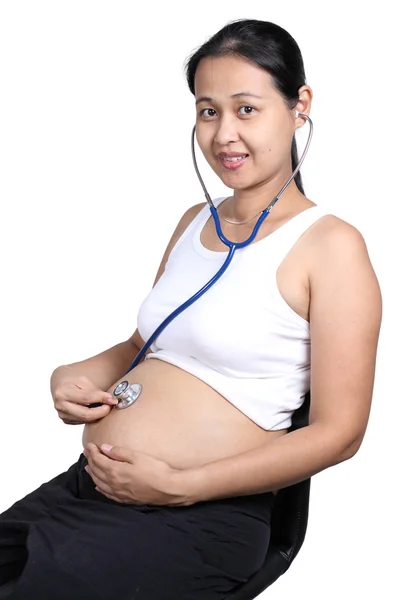 Pregnant woman with stethoscope listening to baby — Stock Photo, Image