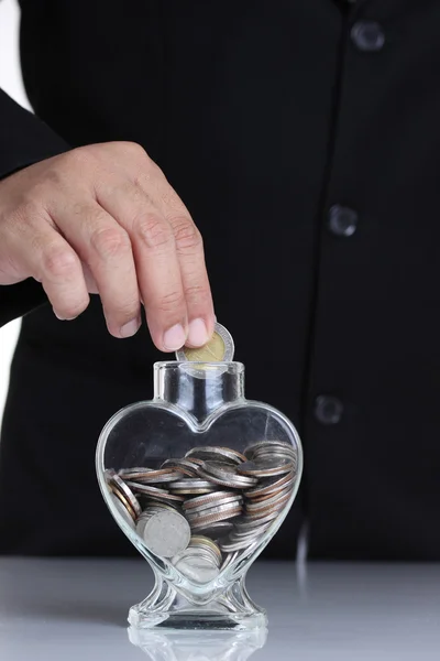 Hand putting a coin into glass — Stock Photo, Image