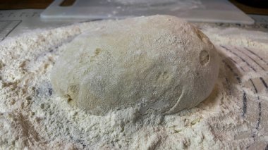 Beyaz ekmek hamurunun, bulanık bir arkaplanı olan ahşap bir masada yakın plan çekimi.