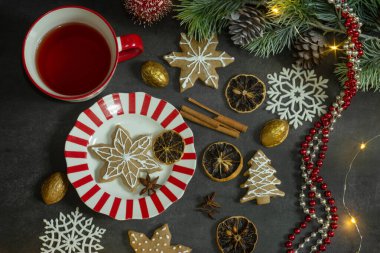 Bir fincan kahve ve zencefilli çörekle noel süslemeleri. Karanlık arka planda noel ağacı dalları. Kopyalama alanı olan üst görünüm. Noel ve yeni yıl konsepti.