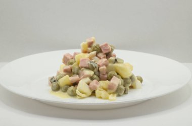 Beyaz arka planda beyaz tabakta Olivier salatası