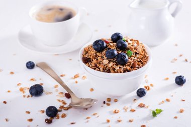 Yoğurtlu müsli, beyaz ahşap arka planda bir fincan kahve. Lezzetli ve sağlıklı kahvaltı..