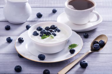 Beyaz ahşap masada yoğurt ve yabanmersini. Sağlıklı ve lezzetli bir kahvaltı..