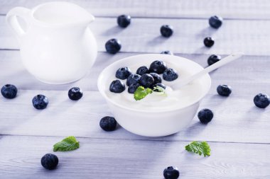 Beyaz ahşap masada yoğurt ve yabanmersini. Sağlıklı ve lezzetli bir kahvaltı..