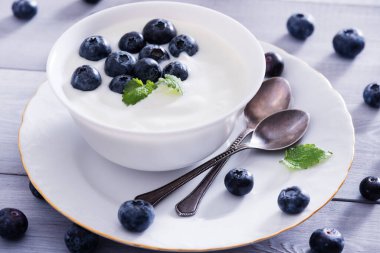 Beyaz ahşap masada yoğurt ve yabanmersini. Sağlıklı ve lezzetli bir kahvaltı..