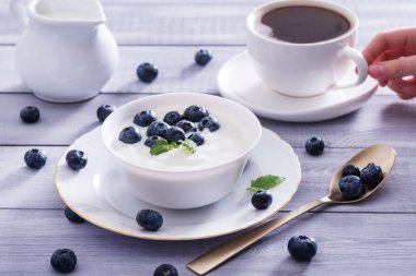Beyaz ahşap masada yoğurt ve yabanmersini. Sağlıklı ve lezzetli bir kahvaltı..