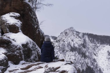 Kız kış dağ manzarasına, bulutlu havaya, kara, turizme, dağa tırmanmaya hayran.