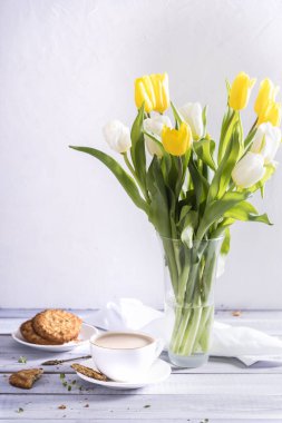 Sabah kahvesi, pasta makaronu ve beyaz ahşap zemin üzerinde bahar beyaz ve sarı laleler. Kadınlar için güzel bir kahvaltı